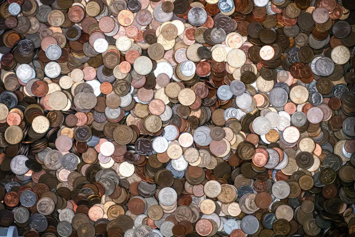 Bilhete de lotaria e moedas espalhadas numa superfície de madeira