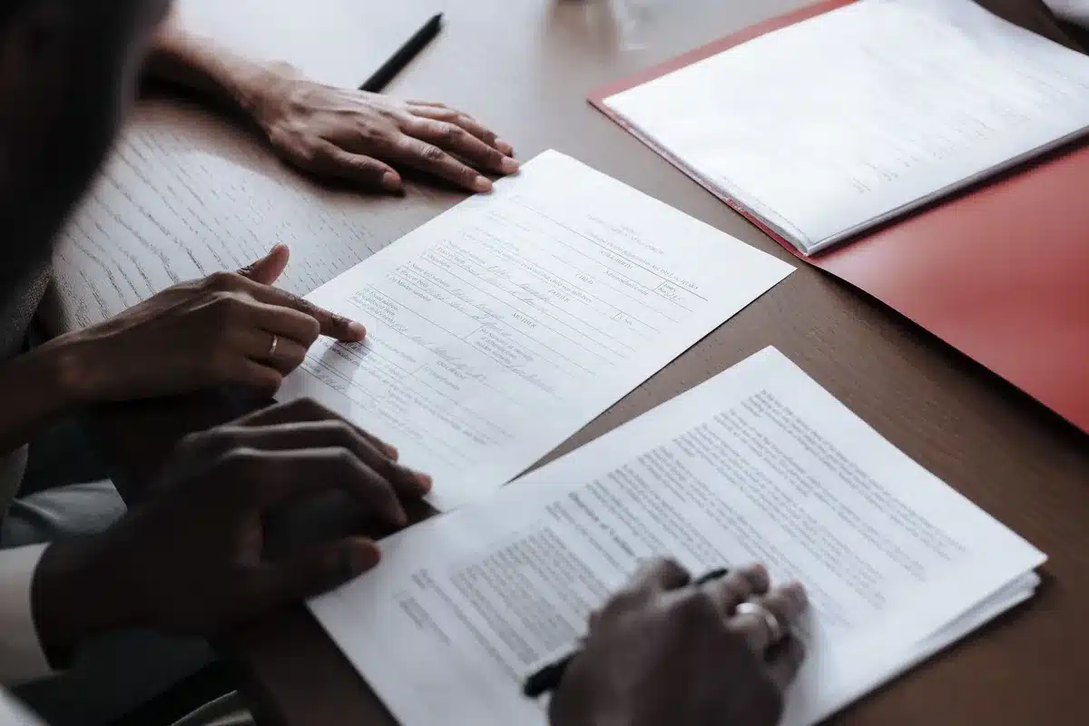 Documentos judiciais e calculadora numa secretária de tribunal, representando litígio sobre compensação