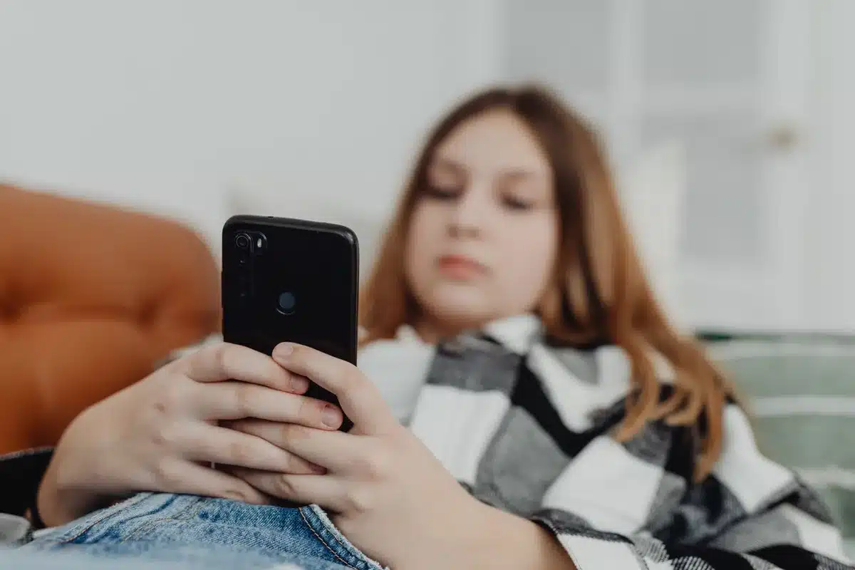 Adolescente absorto no telemóvel, ilustrando o excesso de tempo em ecrãs