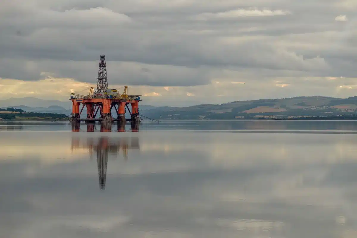 Plataforma de exploração de petróleo em águas profundas com floresta tropical ao fundo