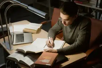 Estudante a estudar numa secretária modesta com livros e computador