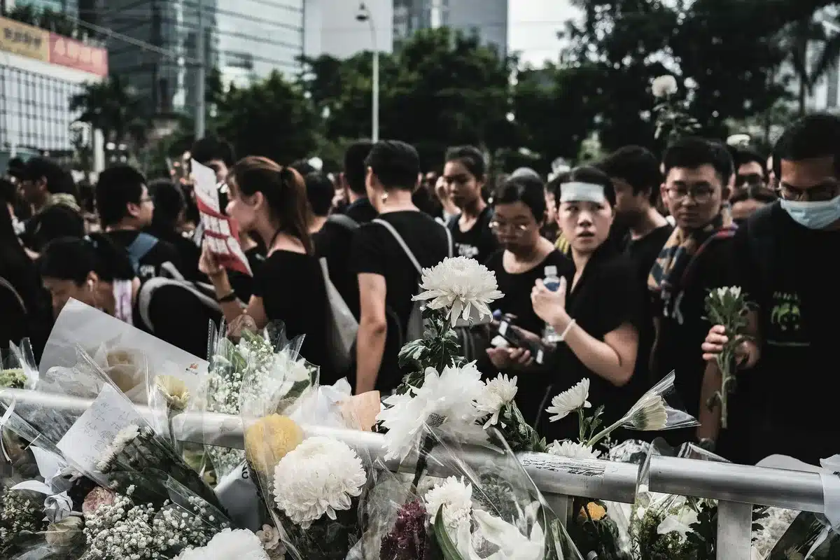 Multidão de pessoas em homenagem fúnebre com flores ao longo da rua