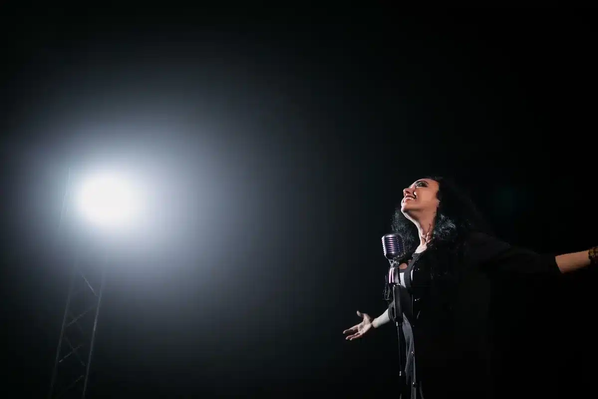 Cantora em palco sob luzes durante apresentação musical
