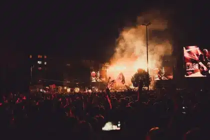 Multidão num festival de verão português com palco ao fundo e bandeiras decorativas