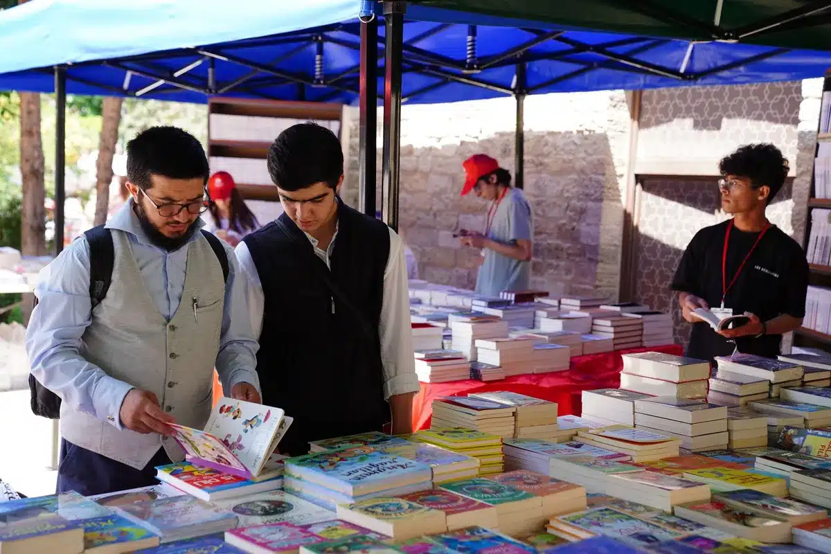 Visitantes a explorar livros nos Jardins do Palácio de Cristal durante a Feira
