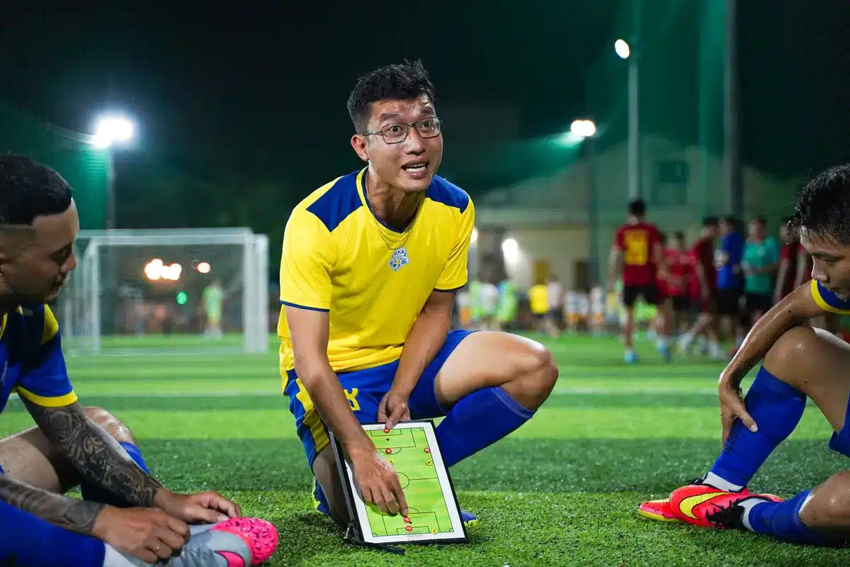 Treinador de futebol a planear táticas e rotações de plantel com a sua equipa