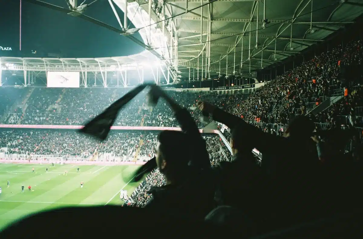 Futebolista a celebrar um golo com os braços levantados num estádio