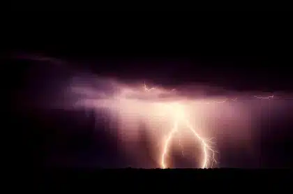 Nuvens de tempestade escuras com chuva intensa e relâmpagos ao fundo sobre paisagem rural