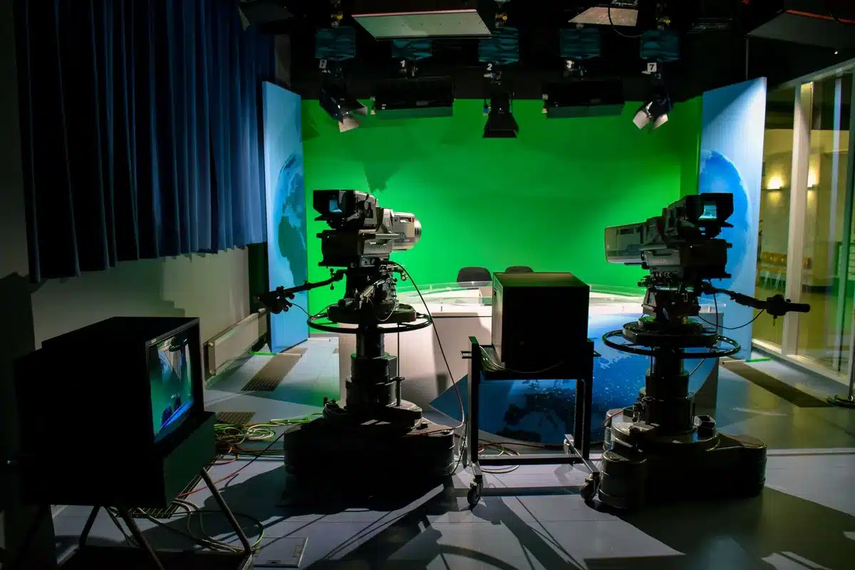 Estúdio de televisão com câmaras e luzes de produção, representando a carreira televisiva da atriz.