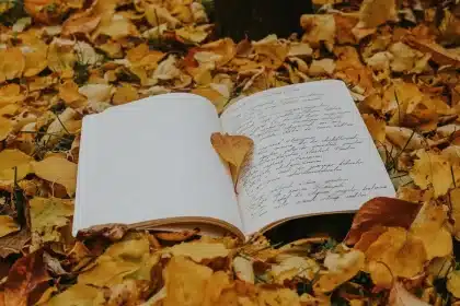 Livro aberto com páginas manuscritas e caneta, simbolizando a criação poética e resistência intelectual.