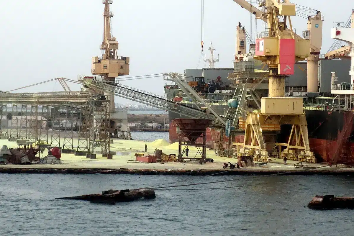 Plataforma de perfuração petrolífera no oceano com estruturas industriais e luzes ao entardecer