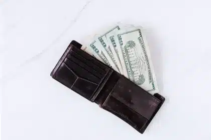 Mãos vazias segurando carteira vazia ao lado de contas e chave de apartamento