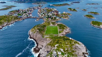 Multidão de adeptos num estádio de futebol italiano ao entardecer, com o campo tático ao fundo