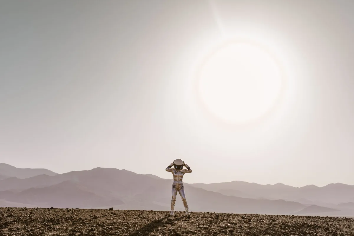 Paisagem de planeta alien&iacute;gena com c&eacute;u laranja e forma&ccedil;&otilde;es rochosas