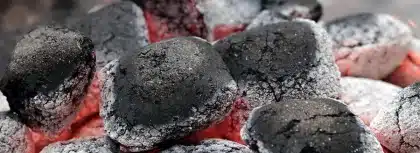 Jerricans empilhados junto a uma viatura comercial na margem de um rio ao amanhecer