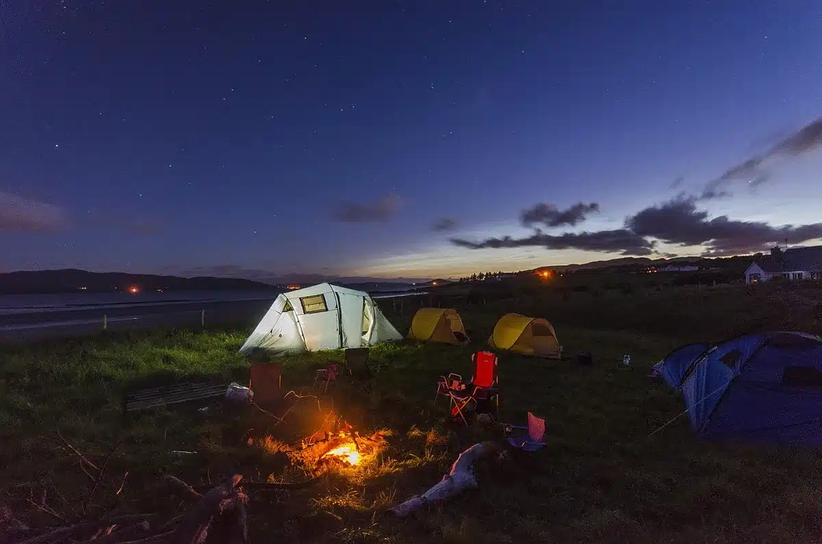 Pessoas reunidas à volta de uma fogueira durante um acampamento noturno