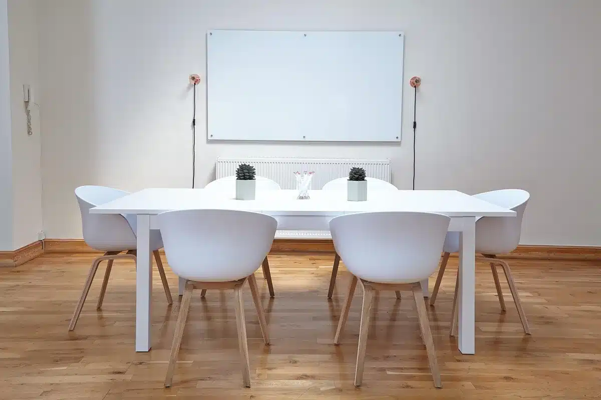 Sala de aula vazia com livros empilhados e quadro branco ao fundo