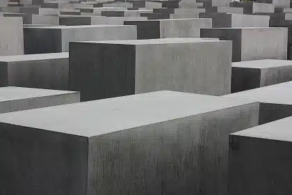 Monumento memorial com arame farpado e céu ao entardecer, evocando a memória histórica do Holocausto