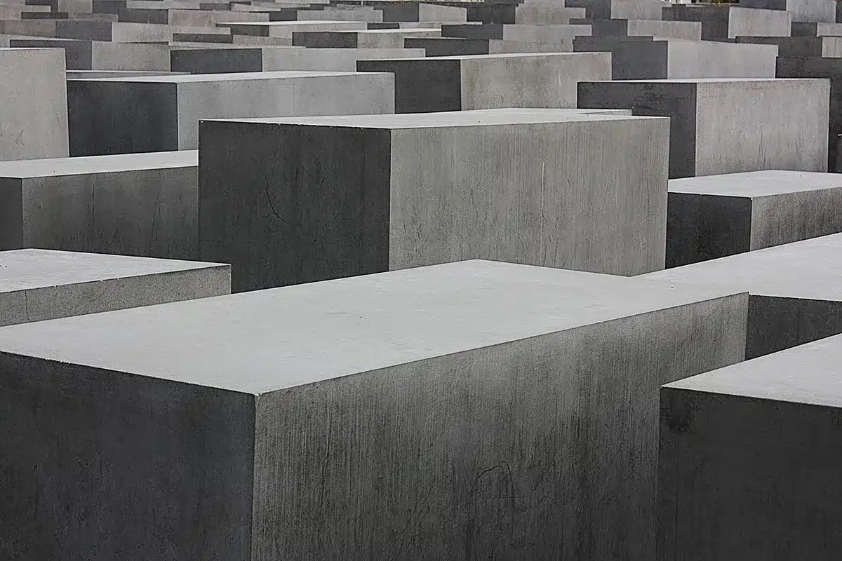 Monumento memorial com arame farpado e céu ao entardecer, evocando a memória histórica do Holocausto