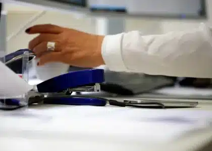 Mãos anónimas com papéis e calculadora sobre mesa, ilustrando crédito à habitação