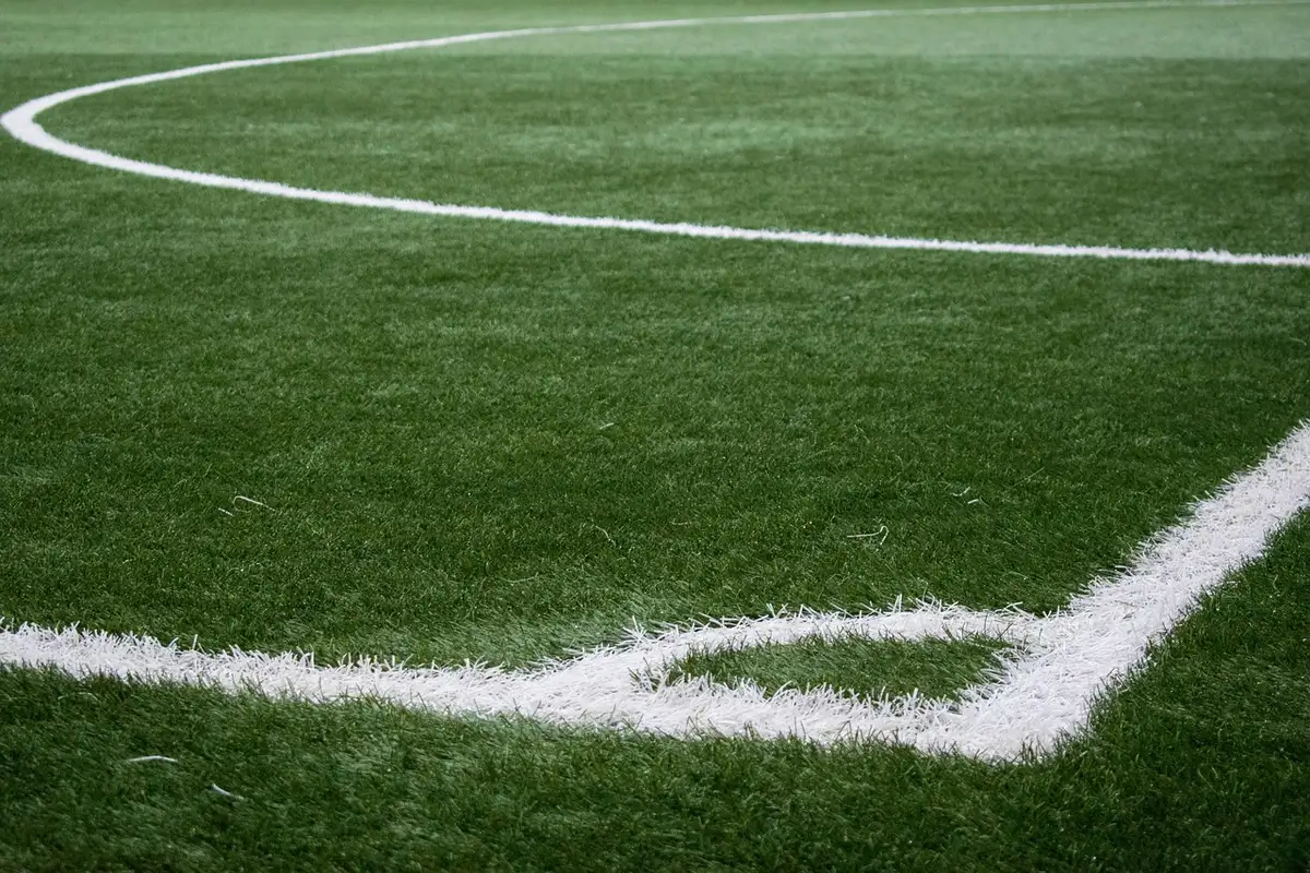 Jogadores correndo com chuteiras rosa fluorescente sobre relva