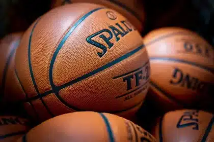 Bola de basquetebol em voo sobre um campo com bancada desfocada e público anónimo
