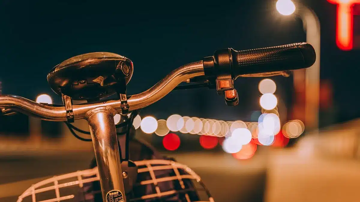 Silhueta das mãos de um piloto nas manetes de uma mota com pista desfocada ao fundo
