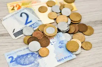 Mãos anónimas a manipular documentos e notas de euro numa secretária de escritório