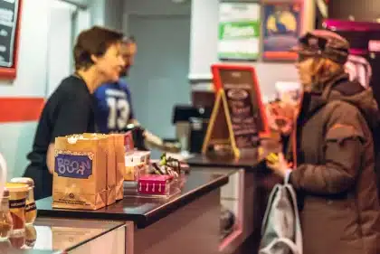 Bilheteiras de cinema com espectadores anónimos em silhueta numa sala moderna