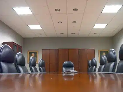 Sala de reunião com silhuetas de delegados e pastas sobre a mesa