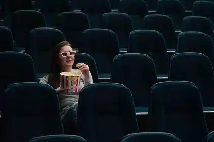 Sala de cinema vazia com cadeiras em primeiro plano e tela desfocada ao fundo