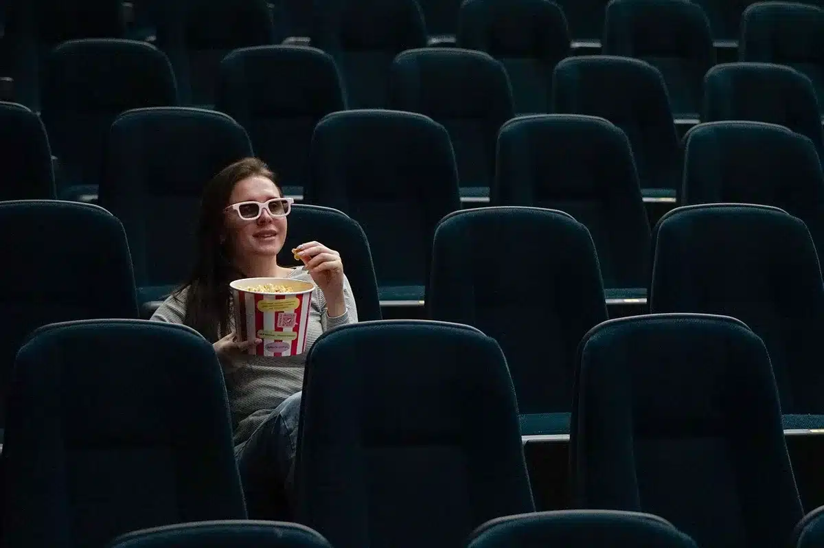 Sala de cinema vazia com cadeiras em primeiro plano e tela desfocada ao fundo