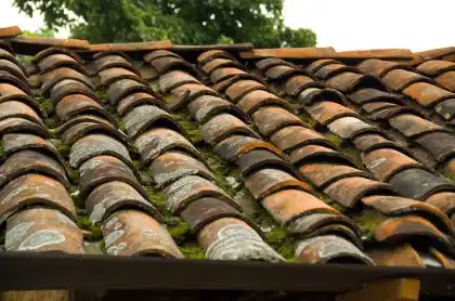 Telhados urbanos e um lote vazio com materiais de construção, sugerindo pressão sobre a oferta habitacional