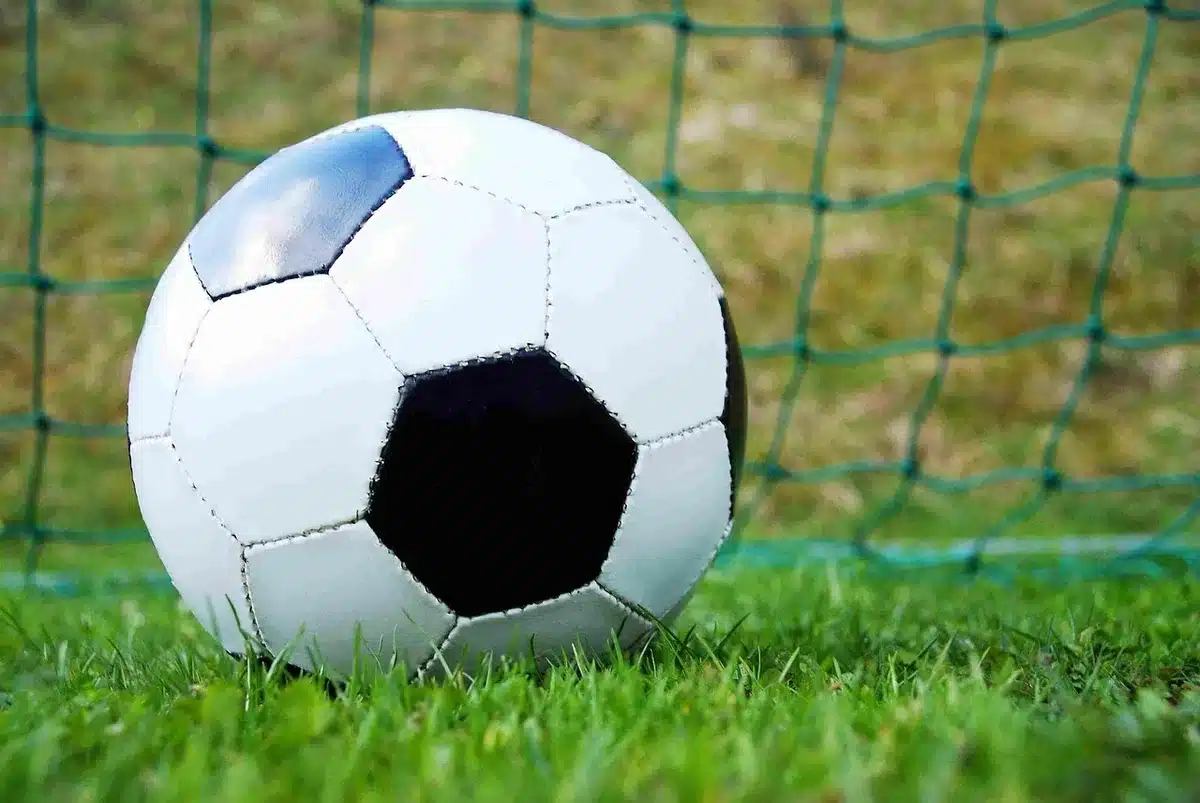 Silhuetas anónimas de adeptos junto a um estádio, bandeira desfocada ao fundo