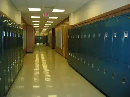 Corredor de escola com mochilas e sapatos anónimos à luz do dia