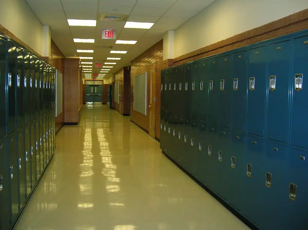 Corredor de escola com mochilas e sapatos anónimos à luz do dia