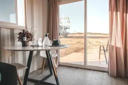 Mãos anónimas seguram documentos e uma calculadora sobre uma mesa, ao fundo um salão parlamentar desfocado