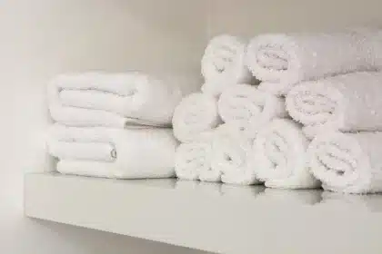 Mãos anónimas a segurar fios de cabelo sobre uma toalha numa casa de banho bem iluminada