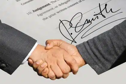 Mãos anónimas sobre pastas e documentos numa mesa de reunião, símbolo de processos administrativos