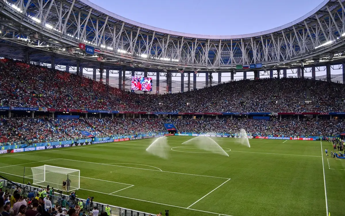 Exterior do Estádio Ullevaal ao anoitecer com uma bola no passeio molhado
